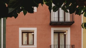A building with a brown facade, a wooden door, and a balcony with a metal railing. - Superior Apartment Pau Suites (La Vila Joiosa)