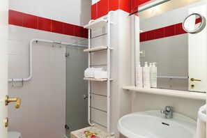 Ein Badezimmer mit Dusche, Toilette, Waschbecken und Ablagen für Pflegeprodukte.
