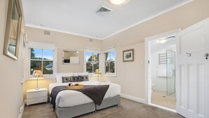 A bedroom with a large bed, a bedside table, a lamp, and a window with a view of trees. - The Foldgarth – late Victorian era farmhouse (Burradoo)