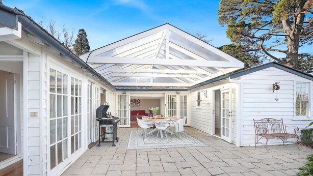 A covered patio with a grill, a dining table with chairs, and a small shed. - The Foldgarth – late Victorian era farmhouse (Burradoo)