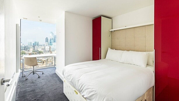 Una camera d'albergo moderna con un letto grande, una scrivania e vista sulla città.