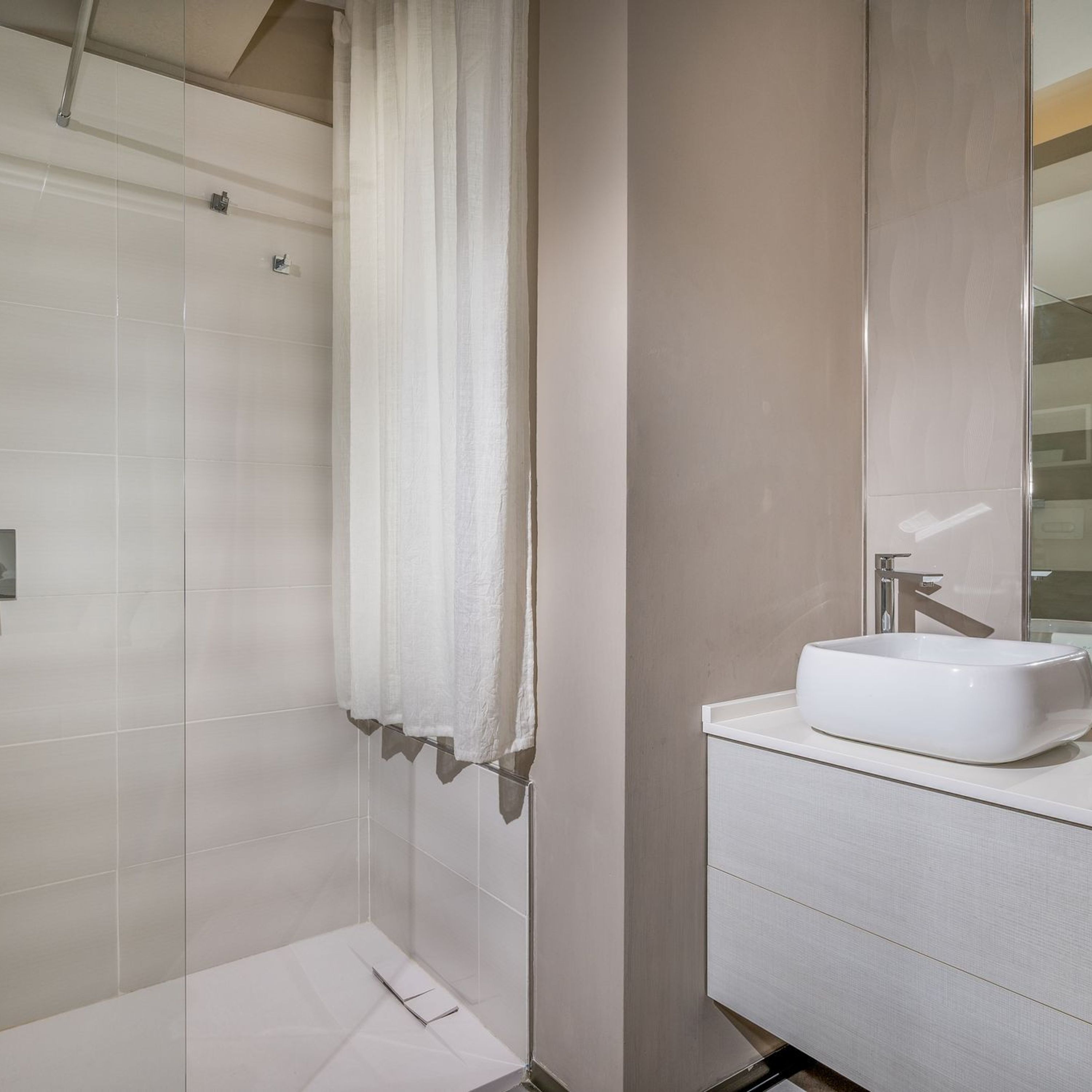 Ein modernes Badezimmer mit Dusche, Waschbecken und Spiegel.