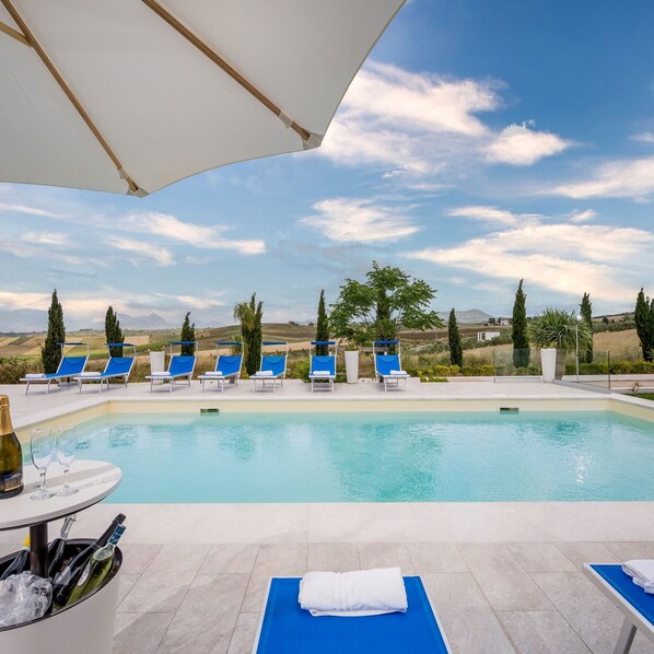 Zona junto a la piscina con sillones de descanso y vistas al campo.