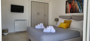 Une chambre à coucher avec un lit, une télévision, un radiateur et un tableau accroché au mur.