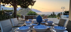 An outdoor seating area with multiple bowls and a decorative vase, overlooking a mountainous landscape. - Villa Ballerina Bianca (Castellammare del Golfo)