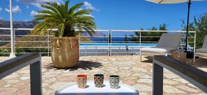 A terrace with a view of the sea, a lounge chair, a large potted plant, and two decorative cups. - Villa Ballerina Bianca (Castellammare del Golfo)