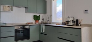A kitchen with a built-in oven, a sink, and a window with a view. - Villa Ballerina Bianca (Castellammare del Golfo)