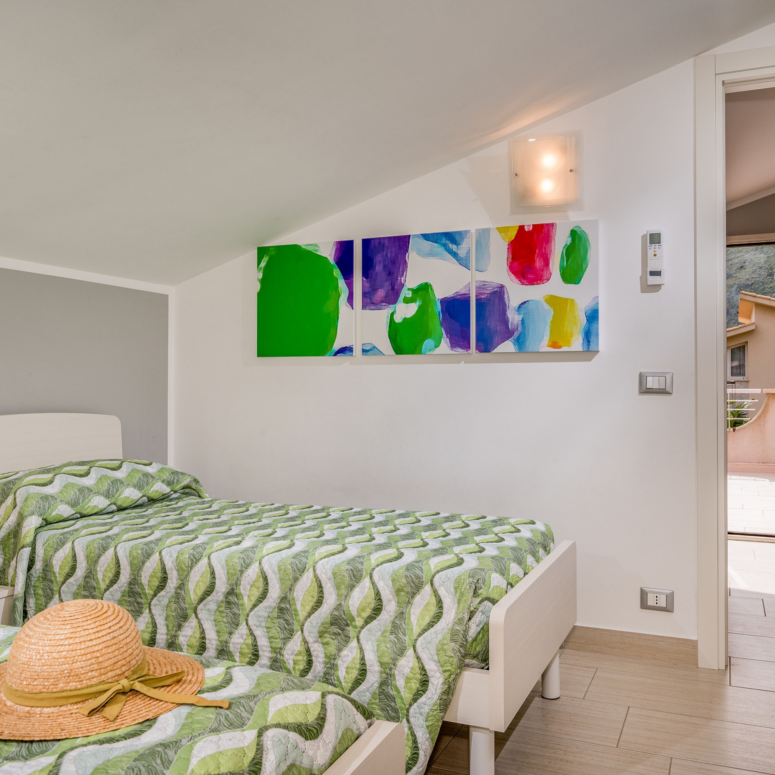 Une chambre à coucher avec un lit, une lampe fixée au mur et une fenêtre.