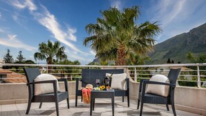 A terrace with wicker furniture, a bottle of wine, and a sun hat. - Villa Jacqueline con Piscina Privata 8 Posti Letto (Castellammare del Golfo)