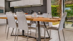 A modern kitchen with white cabinets, a wooden dining table, and four chairs. - Villa Jacqueline con Piscina Privata 8 Posti Letto (Castellammare del Golfo)