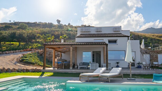 A modern house with a pool, outdoor seating, and a view of the hills. - Villa Majestatis in Scopello (Castellammare del Golfo)