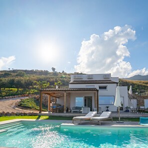Ein modernes Haus mit Pool, Sitzgelegenheit im Freien und Blick auf die Hügel.