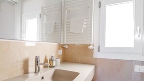 Een moderne badkamer met een grote wastafel, een spiegel en een raam.