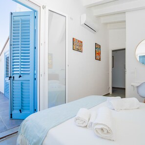 Une chambre d’hôtel comprenant un lit, une salle de bain et une porte donnant sur un balcon.