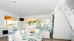 Een moderne keuken met een glazen eettafel, witte stoelen en een schaal fruit.