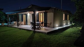 A modern house with a covered patio, outdoor seating, and a well-lit entrance. - Giardino di Limoni Eco Friendly Villa (Noto)