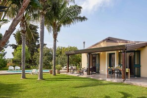 A house with a covered patio, a swimming pool, and a well-maintained lawn. - Giardino di Limoni Eco Friendly Villa (Noto)