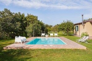 A rectangular swimming pool with a tiled deck, surrounded by white lounge chairs and a well-maintained lawn. - Giardino di Limoni Eco Friendly Villa (Noto)