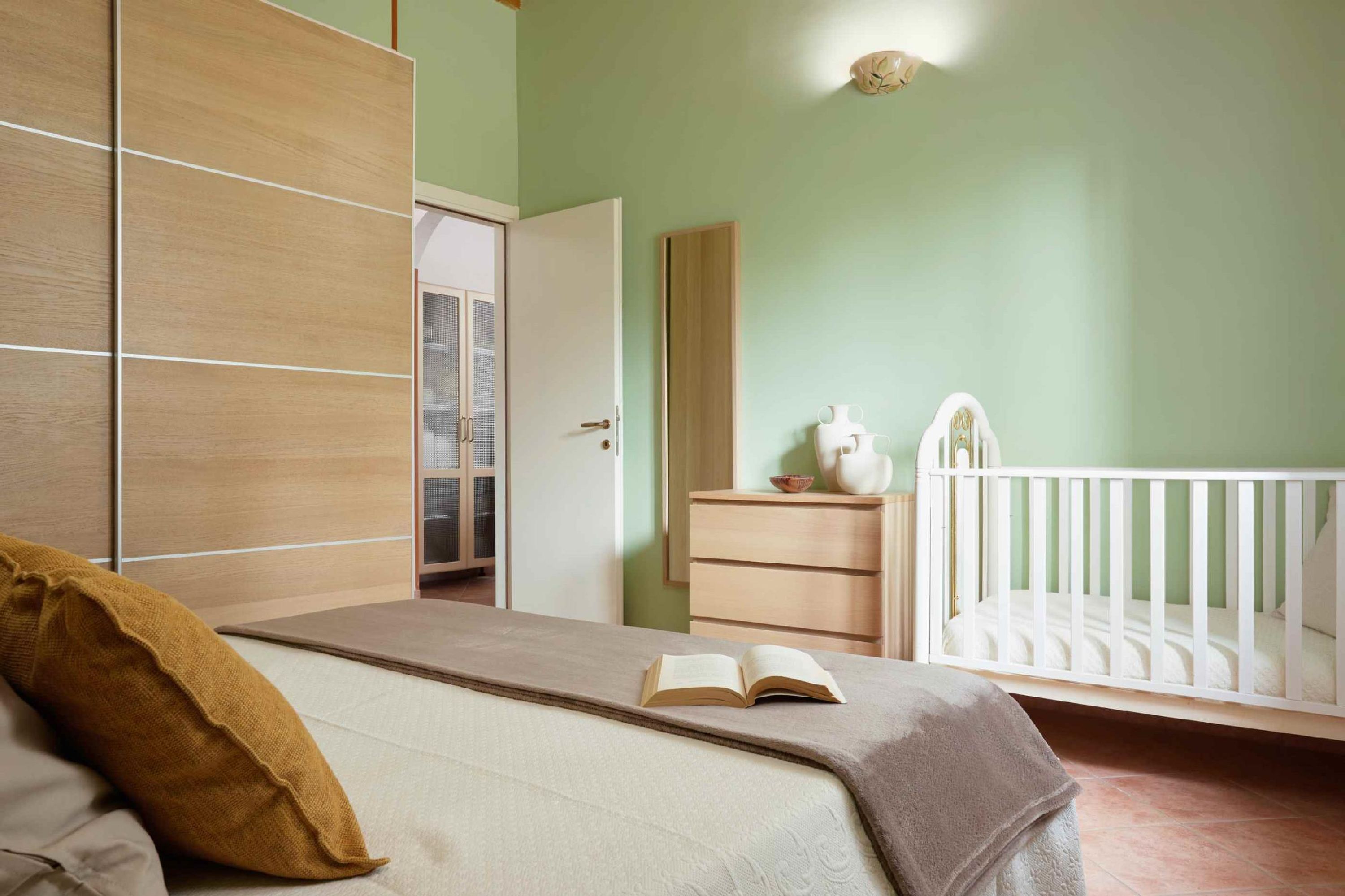 A bedroom with a bed, a crib, a dresser, and a wardrobe.