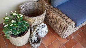 Wicker furniture, a potted plant, and a lantern on a tiled floor.