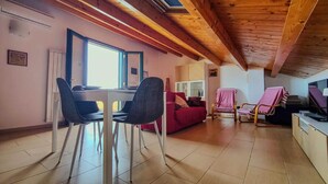 A cozy living room with a dining area, wooden ceiling beams, and a television. - Apartment Eucaliptus sea View (Avola)