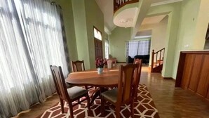 Un espace repas avec une table et des chaises en bois, un tapis à motifs et un escalier menant à un autre niveau.