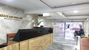 A hotel reception area with a marble wall, a reception desk, and a seating area. - Ngoc Anh Hotel Da Lat (Lam Vien - Da Lat)