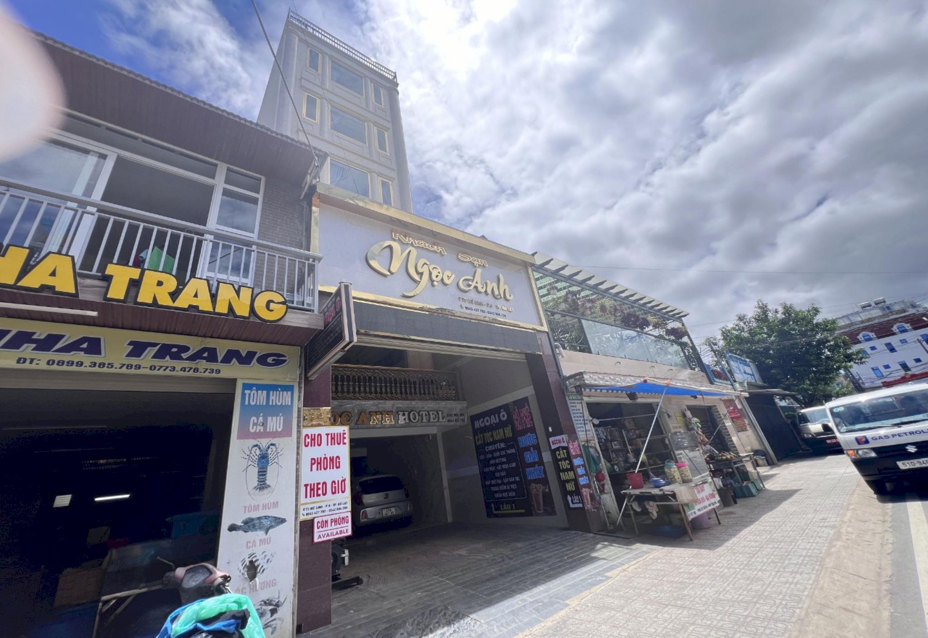 A hotel named 'Nghe Anh' with a signboard, a visible entrance, and a parked car outside.