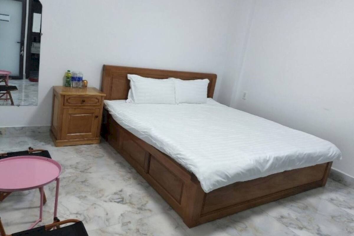 A single bed with a wooden frame and white bedding in a room with a marble floor.