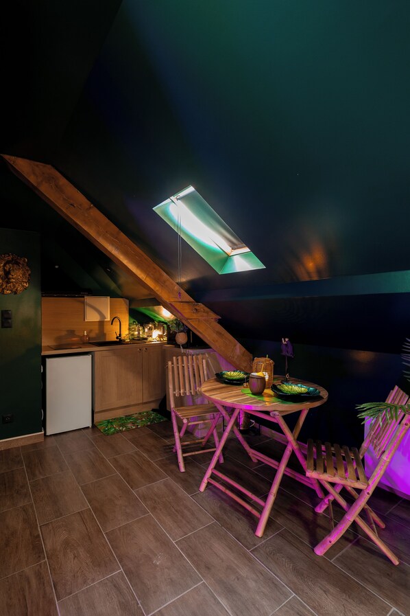 Una cocina acogedora con armarios de madera, un refrigerador pequeño y una zona de comedor con mesa y sillas.