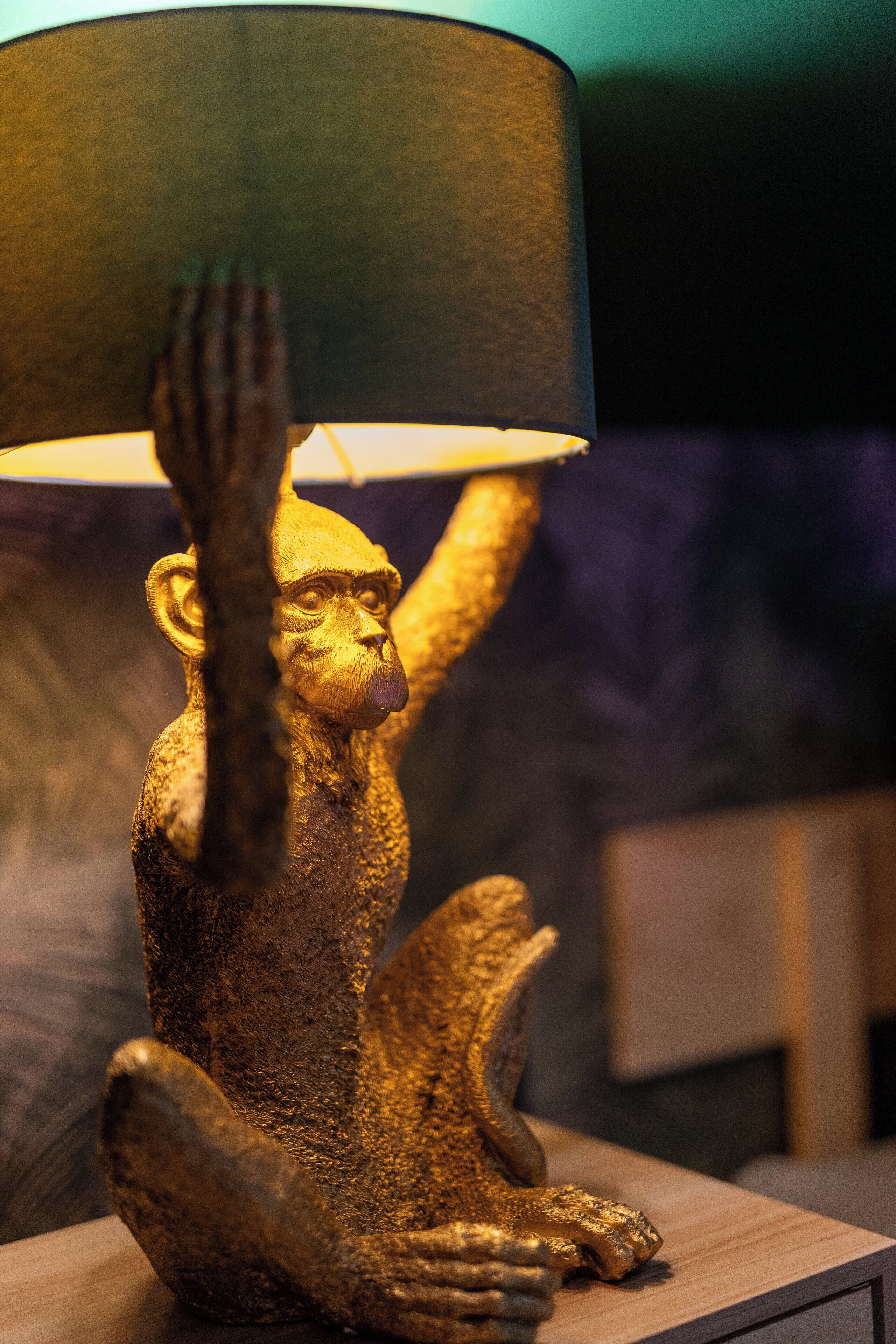 Una scultura dorata di un macaco che tiene in mano una lampada.