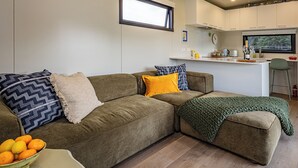 Un salon moderne avec un canapé, un pouf et un saladier rempli d’oranges.