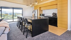 Una cocina moderna con una isla grande, electrodomésticos negros y armarios de madera.