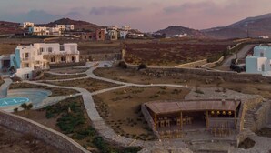 Un complejo turístico con varias edificaciones, piscina y un área exterior cubierta con asientos.