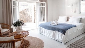 Un dormitorio con cama, muebles de mimbre y vistas al exterior.