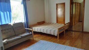 A bedroom with a bed, a sofa, a wooden wardrobe, and a window with curtains. - Saimaa Hirsilinna (Mikkeli)