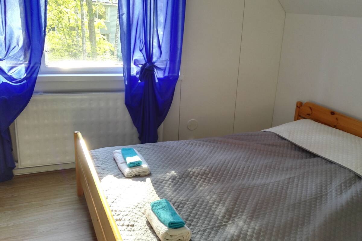 A bedroom with a bed, a window with curtains, and a radiator.
