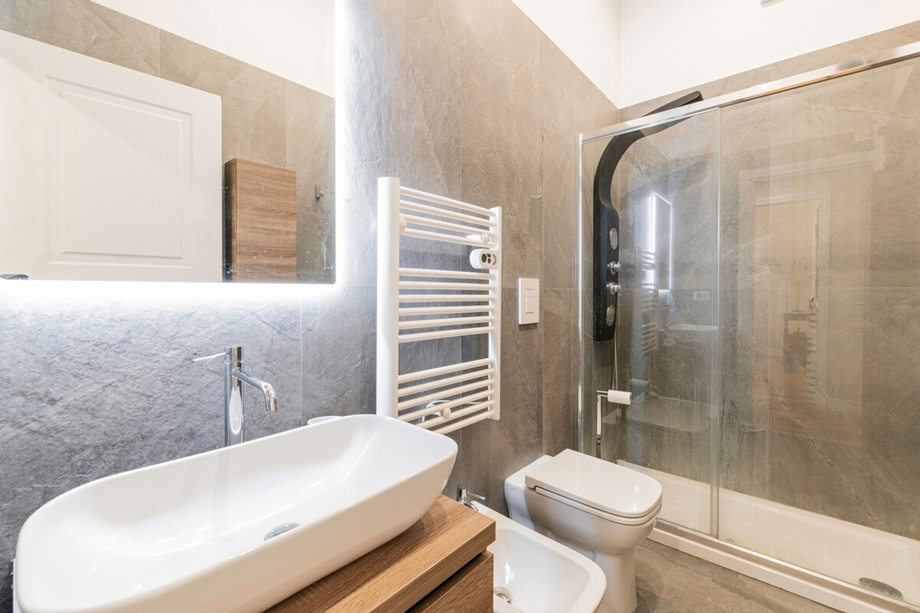 A modern bathroom with a freestanding bathtub, a toilet, and a glass-enclosed shower.