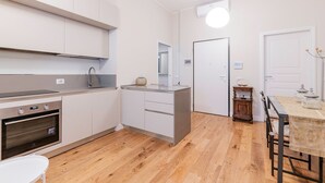 A modern kitchen with white cabinets, a built-in oven, and a dining area with a table and chairs. - Appartamento Tiepolo Elegant Venue in Porta Venezia (Milan)