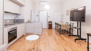 A modern kitchen with white cabinets, a built-in oven, and a dining area with a table and chairs. - Appartamento Tiepolo Elegant Venue in Porta Venezia (Milan)