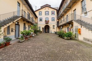 A courtyard with a central archway, potted plants, and a brick floor. - Moderno Loft nel Cortile di un Casale Storico (Corsico)