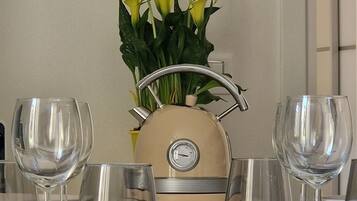 A dining table set with wine glasses, bowls, and a vintage-style kettle.