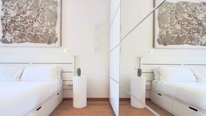 A modern bedroom with a mirrored wall, two beds, bedside tables, and a large floral painting. - Moderno Bilocale con Terrazzo e Parcheggio (Florence)