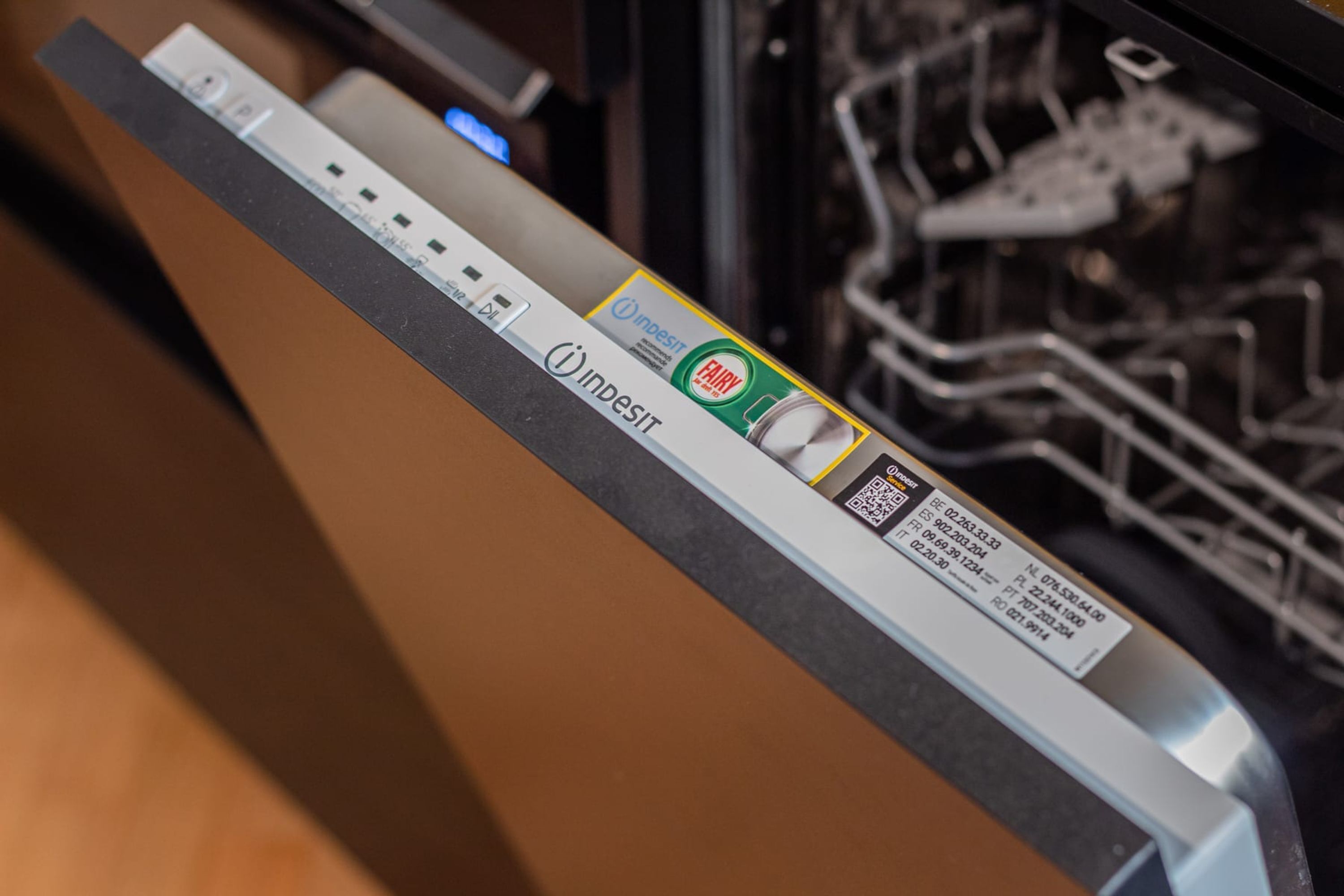 A dishwasher with a control panel and a label indicating it is an Indesit brand.