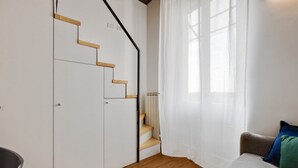 A modern living room with a staircase, a sofa, and a window with sheer curtains. - Cozy Penthouse With Stunning View Balcony (Milan)