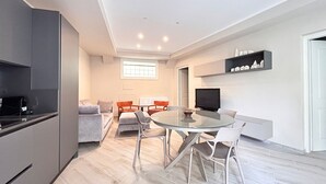 A modern living room with a glass dining table, grey sofas, and a TV mounted on the wall. - Modern Apartment in the Heart of Pisa (Pisa)