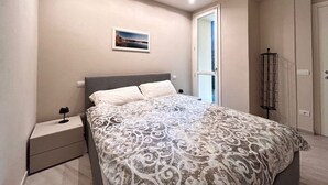 A bedroom with a bed, bedside table, and a window. - Modern Apartment in the Heart of Pisa (Pisa)