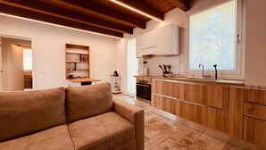 A modern kitchen with wooden cabinets, a built-in oven, and a large window. - Villetta Monte San Lorenzo (Monte San Pietro)