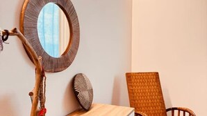 A wooden console table with a mirror, a woven chair, and a decorative branch. - Villetta Monte San Lorenzo (Monte San Pietro)