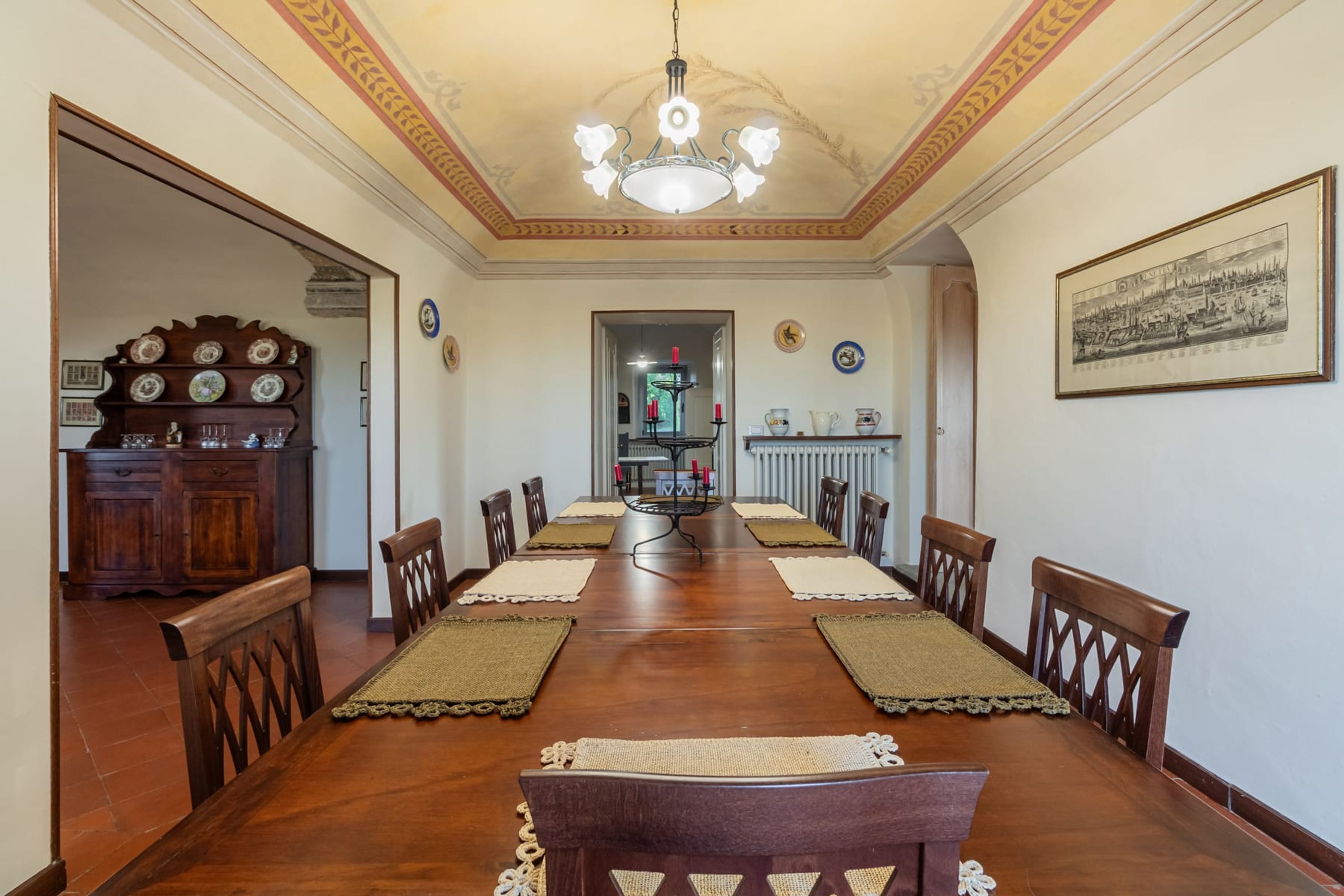 A dining room with a long wooden table, chairs, and a chandelier.